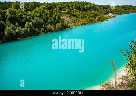 Schöne Landschaft - ein Bergsee mit ungewöhnlich hell türkisfarbenem Wasser. Steinküste mit grünen Bäumen. Stockfoto