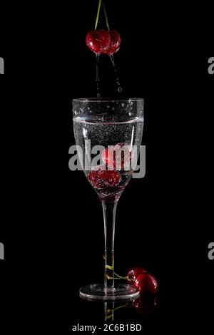 Hochgeschwindigkeits-Blitzfotografie mit Kirschen, die in Weinglas spritzen Stockfoto
