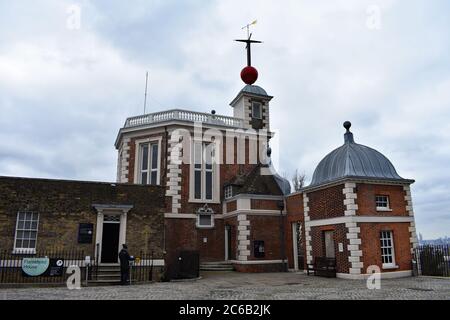 Ein Besucher, der das Flamsteed House am Royal Observatory im Greenwich Park betritt. Ein roter Zeitball und Wetterflügel über dem Octagon Room. Stockfoto