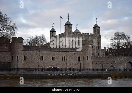 Der Tower of London von der Themse aus gesehen an einem bewölkten Tag. Eingang zum Verrätertor-Schild sichtbar. Die Weißen Türme eine Flagge am vollen Mast. Stockfoto