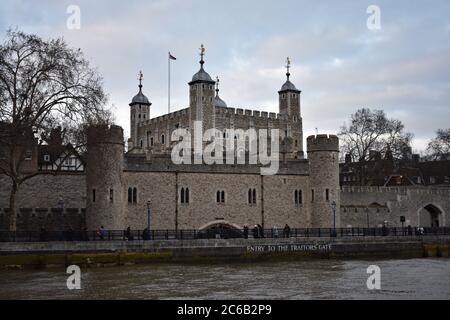 Der Tower of London von der Themse aus gesehen an einem bewölkten Tag. Eingang zum Traitors Gate Schild, sichtbar über dem Wasser in weißer Schrift. Stockfoto