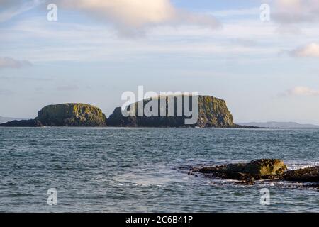 Blick auf das Meer vom Ballintoy Hafen mit großen Felsformationen in der Mitte und Rathlin Insel in der Ferne Stockfoto