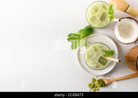Iced Latte grüner Matcha Tee mit Kokosnuss auf weißem Hintergrund. Blick von oben. Stockfoto