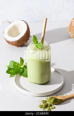 Iced Latte grüner Matcha Tee mit Kokosmilch garnieren Minze auf weißem Hintergrund. Stockfoto