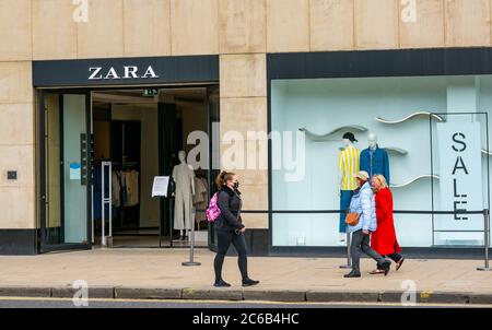 Die Käufer kommen an Zara Bekleidungsgeschäft vorbei; eine Frau trägt eine Gesichtsmaske während der Pandemie, Princes Street, Edinburgh, Schottland, Großbritannien Stockfoto