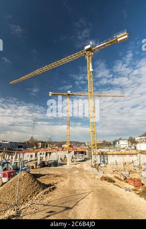 Unbefestigte Straße, die zu einer Baustelle mit zwei Kränen führt Stockfoto