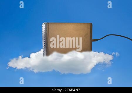Festplatte auf einer Wolke am blauen Himmel als Symbol für Cloud-Speicherung Stockfoto