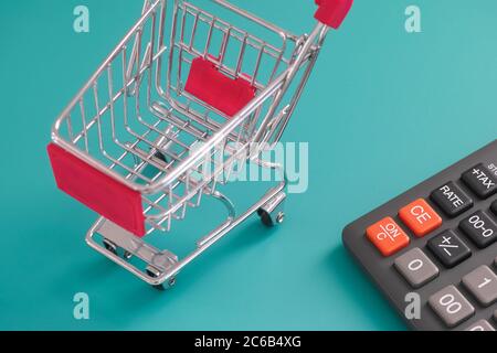 Ein leerer Einkaufswagen, der in der Nähe eines Rechners steht. Nahaufnahme. Stockfoto