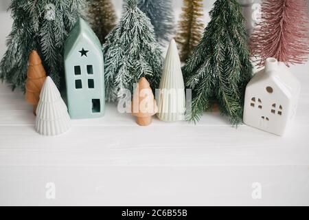 Frohe Feiertage. Miniatur gemütliches Dorf, Keramik Häuser, Holz und handgemachte weihnachtsbäume. Weihnachten kleine Häuser und Bäume auf weißem Hintergrund. Fe Stockfoto