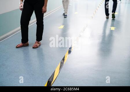 Mitarbeiter Im Büro Folgen Den Markierungen Des Social Distancing Tape Auf Dem Boden Stockfoto