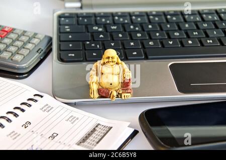 Buddha-Statue auf einem Laptop vor der Büroausstattung Stockfoto