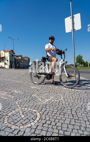 Mann, der während des Tragens auf einem Fahrradweg radeln muss Ein Helm Stockfoto