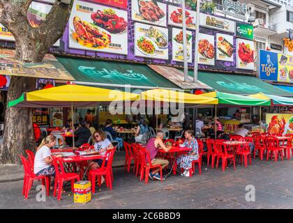 Menschen, die vor einem lokalen Restaurant auf Jalan Alor sitzen, einer Straße im Goldenen Dreieck, die für ihr Essen und Trinken berühmt ist, Kuala Lumpur, Malaysia Stockfoto