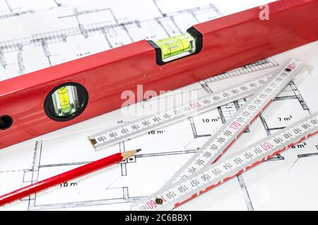 Wasserwaage, Bleistift und Maßstab auf einem Bauplan Stockfoto