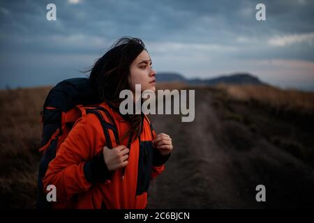 Portrait eines touristischen Mädchens mit Rucksack. Junge schöne Frau, die in den Bergen unterwegs ist Stockfoto
