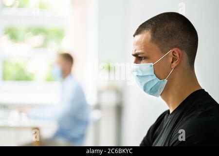 Junge Männliche Arbeiter Im Büro Trägt Medizinische Gesichtsmaske Stockfoto