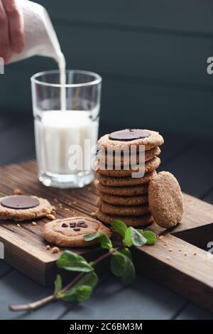 Vegetarische Süßigkeiten für gesunde Zucker kostenloses Frühstück. Erdnussbutter und Mandelgebäck mit Schokoladentropfen serviert mit Pflanzenmilch im Glas und Minze auf Stockfoto