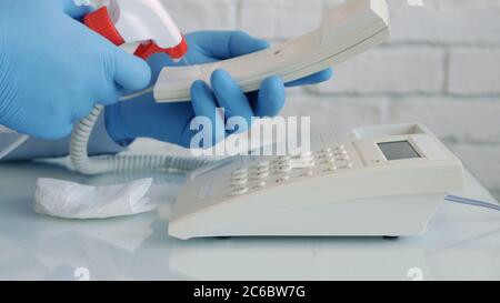 Mann trägt Schutzhandschuhe in den Händen Reinigung und Desinfektion eines Telefons mit einem Spray und feuchten Wischtüchern Stockfoto