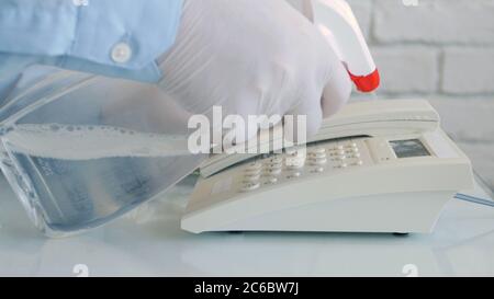 Mann trägt Schutzhandschuhe in den Händen Reinigung und Desinfektion eines Telefons mit einem Spray und feuchten Wischtüchern Stockfoto