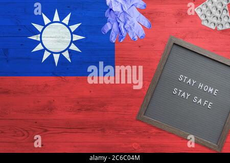 Taiwan Flagge Hintergrund auf Holztisch. Stay Home Schreibtafel, OP-Handschuhe, Pillen mit minimalem nationalen Covid 19 Konzept. Stockfoto
