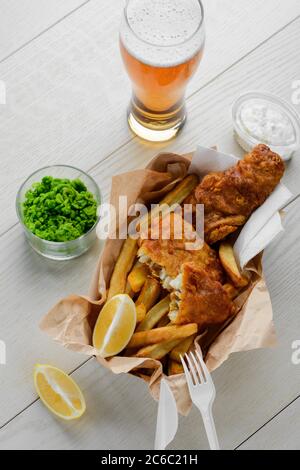 Bier, zerschlagene Fische und Pommes. Pürierte grüne Erbsen und Salat Stockfoto