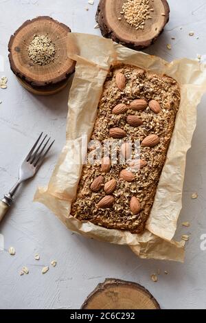 Selbstgemachter glutenfreier, zuckerfreier vegetarischer Teig. Haferflockenbrot mit Samen und Nüssen frisch in Papier gebacken serviert mit ganzen Flachs und Amaranth Samen Stockfoto
