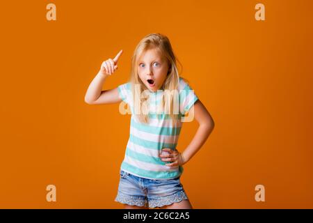 Portrait eines glücklichen blonden Mädchens in einem blauen T-Shirt auf gelbem Hintergrund. Emotionen des Kindes, Platz für Text Stockfoto