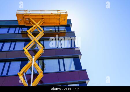 Moderne Gebäudefassade Reparatur mit einem hohen Scherenlift mit einer Plattform Stockfoto