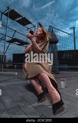 Attraktive Glamouröse Frau In Stilvollem Kleid Auf Baustelle Tun Make-up und sitzen an Beton Ziegel Stockfoto