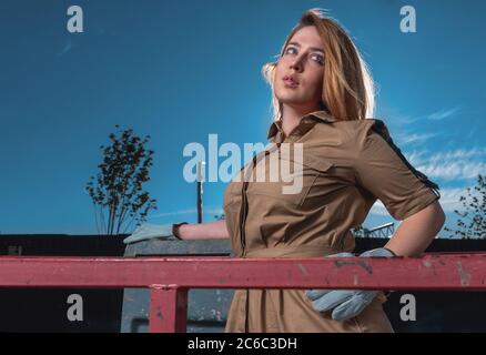 Schöne glamouröse Frau in stilvollen Kleid und Arbeiter Handschuhe an Construction Cradle Stockfoto