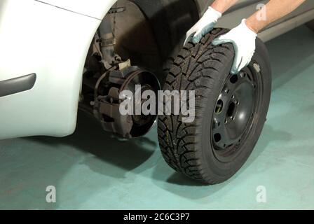 Mann wechselt Autoreifen. Automechaniker in einer Werkstatt Reifenwechsel. Stockfoto