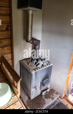 Traditioneller alter Holzofen mit eingebautem Wasserkocher in einer finnischen Sauna Stockfoto