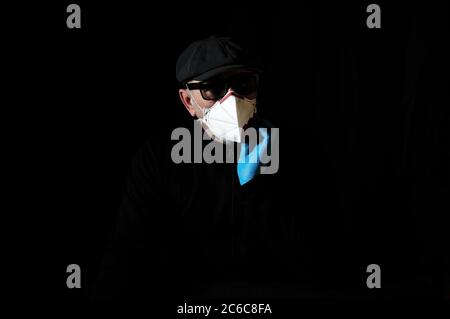 Ein älterer Mann in einem Atemschutzgerät und Handschuhen zum Schutz gegen Covid-19 Stockfoto