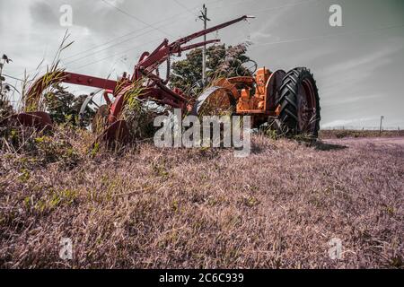 Ein Oldtimer-Traktor und sein Pflug auf einem Trockenland verlassen. Stockfoto