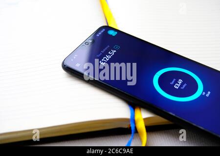 Stone / UK - 8. Juli 2020: Starling Bank App zeigt das Gleichgewicht auf dem Bildschirm des Mobiltelefons, die auf der Oberseite des Geschäftstagebuch platziert. Stockfoto