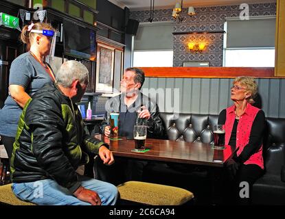 Barmaid in schützender Vollmaske erklärt die neuen Regeln für Kunden in Pub nach Pandemie Einschränkungen aufgehoben werden Stockfoto