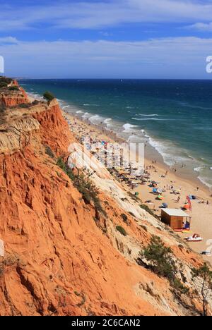 Portugal, Algarve, Albufeira. Teilansicht des langen Strandabschnitt bei Olhos de Agua in der Hochsaison. Von der Klippe aus gesehen. Stockfoto