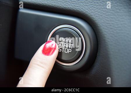 Weibliche Finger auf dem Knopf, um den Motor des Autos zu aktivieren. Frauen aktiviert Taste, um zu starten und zu stoppen für Auto-Motor. Stockfoto