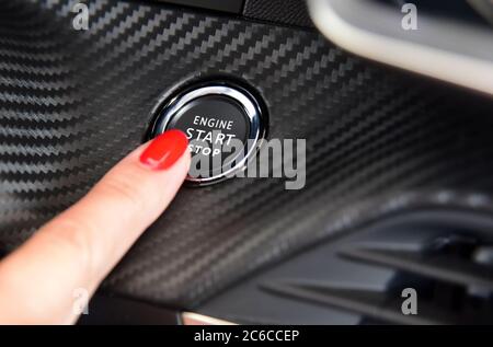 Weibliche Finger auf dem Knopf, um den Motor des Autos zu aktivieren. Frauen aktiviert Taste, um zu starten und zu stoppen für Auto-Motor. Stockfoto