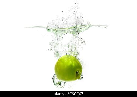 Ein grüner Apfel fällt in Wasser auf weißem Hintergrund mit Spritzern, Tropfen und Blasen. Stockfoto
