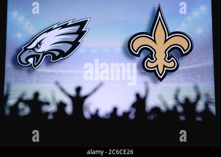 Philadelphia Eagles vs. New Orleans Saints. Fans unterstützen NFL Game. Silhouette der Unterstützer, große Leinwand mit zwei Rivalen im Hintergrund. Stockfoto