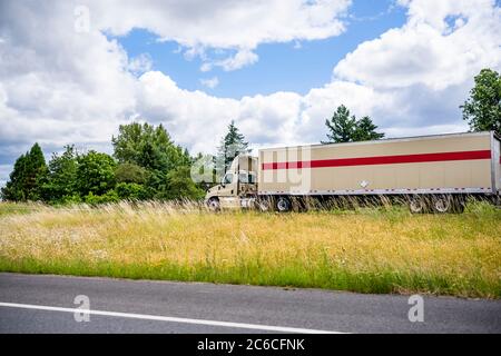 Classic beige leistungsstarke Tag Kabine Diesel Big Rig Semi-Truck mit niedrigen Kabine und aerodynamischen Dach Spoiler Transport von Fracht in trockenen van semi Trailer läuft Stockfoto