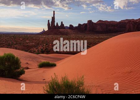 Sanddünen im Monument Valley mit Totem Pole und Yei Bi Chei Formationen im Hintergrund bei Morgenlicht. Monument Valley im Norden Arizonas. Stockfoto