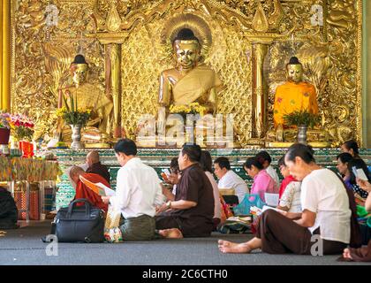 Gläubige beten vor vergoldeten Buddha-Statuen an der Shwedagon Pagode in Yangon, Myanmar Stockfoto