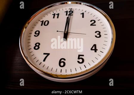 Ein Blick von oben auf runde weiße Wanduhr isoliert auf Holztisch Stockfoto