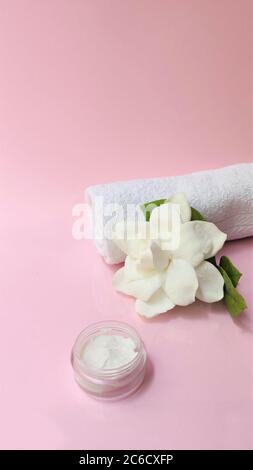 Spa-Einstellung und Spa Hintergrund Komposition mit weißen Gardenia Blume auf rosa Hintergrund. Vertikale Foto Handtuch, Kerzen, Blumen, Steine . Massage, oder Stockfoto