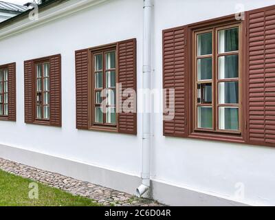 Reihe von klassischen Holzfenstern mit Fensterläden an der weißen Gebäudefassade Stockfoto