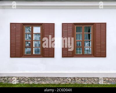 Zwei traditionelle Fenster mit offenen Holzfenstern an der Stuckwand des alten Gebäudes Stockfoto