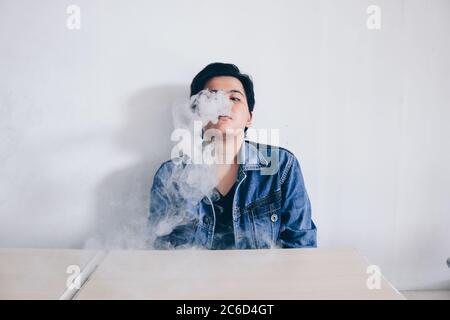 Asiatische schöne kurze Haare Mädchen tragen Jeans Jacke ist Rauchen elektronische Zigarette oder vaping Vape auf weißem Hintergrund Stockfoto