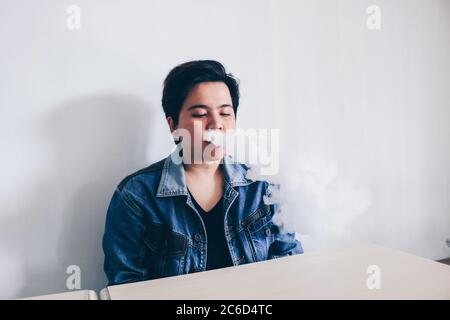 Asiatische schöne kurze Haare Mädchen tragen Jeans Jacke ist Rauchen elektronische Zigarette oder vaping Vape auf weißem Hintergrund Stockfoto